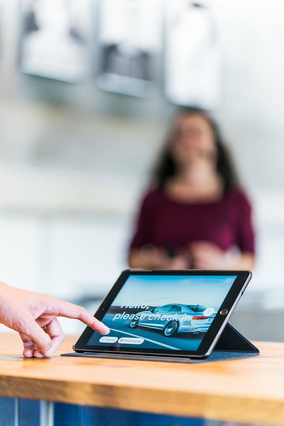 Käsi napauttaa tablettiin, jossa näkyy digitaalinen auton sisäänkirjautuminen.